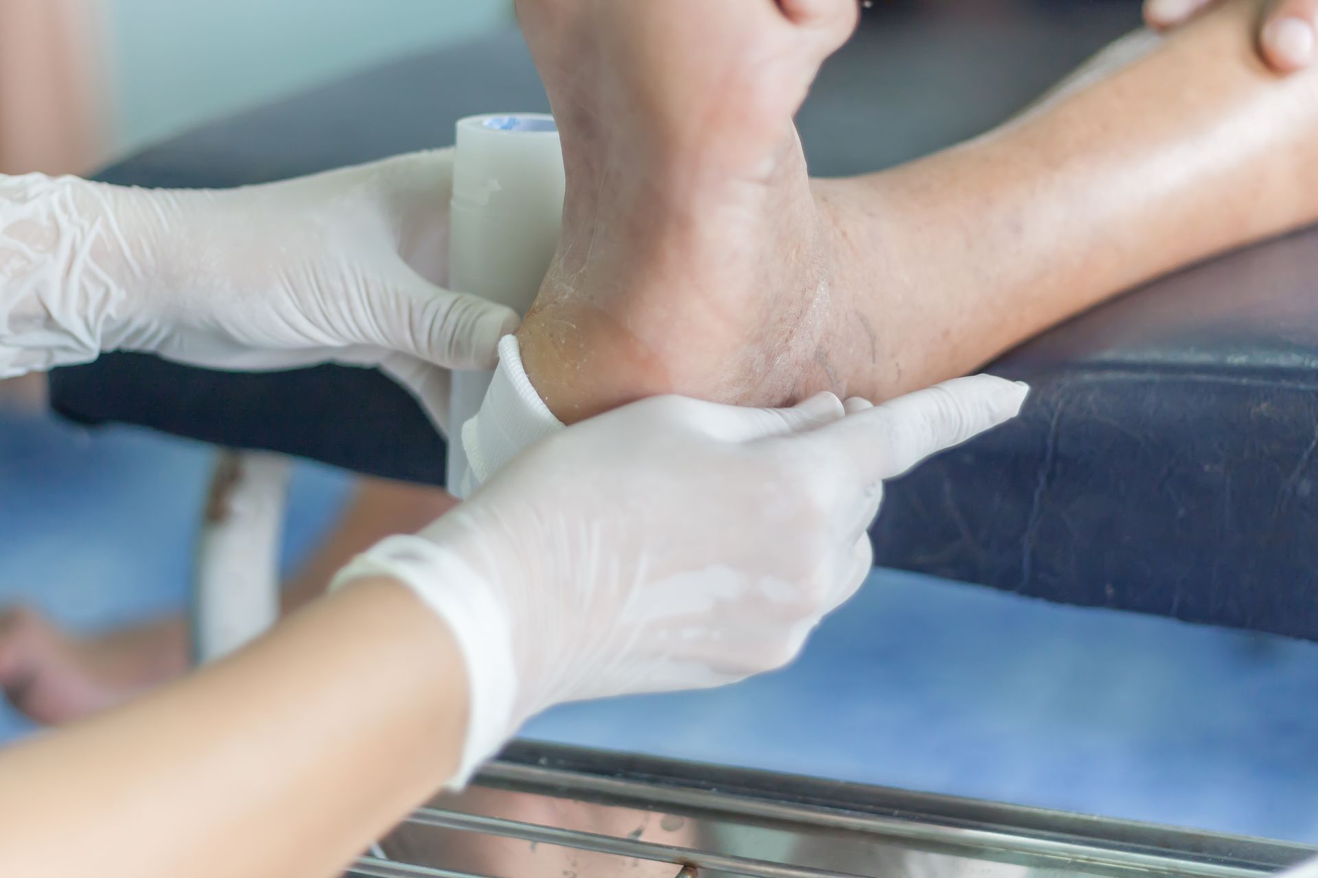 A person's foot being bandaged by a person wearing gloves.