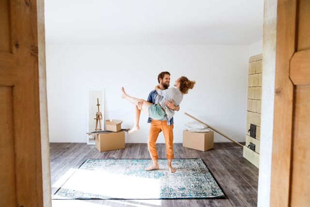 A man is carrying a woman in his arms in an empty room.