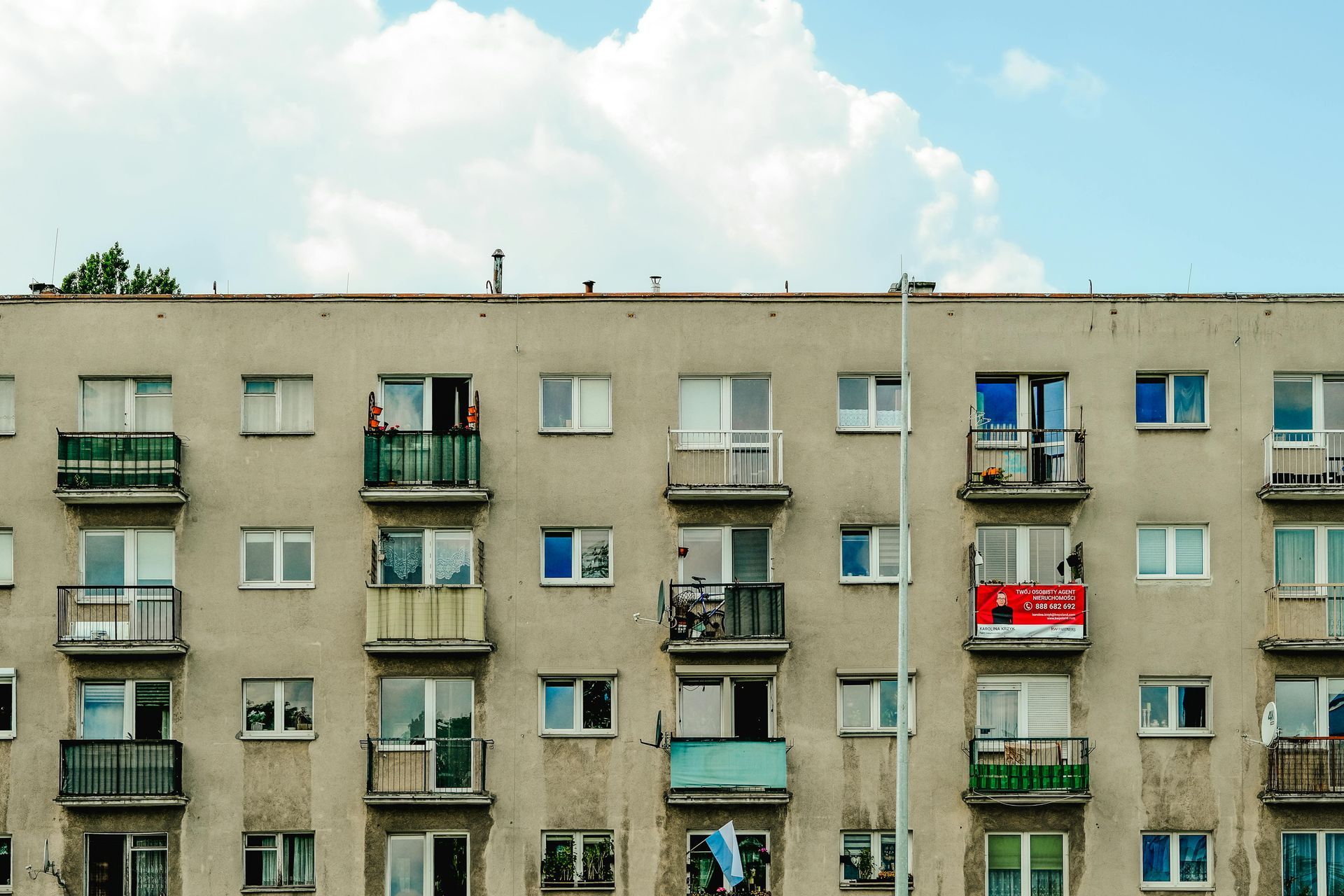 Apartment building facade with balconies and colorful laundry against a cloudy sky