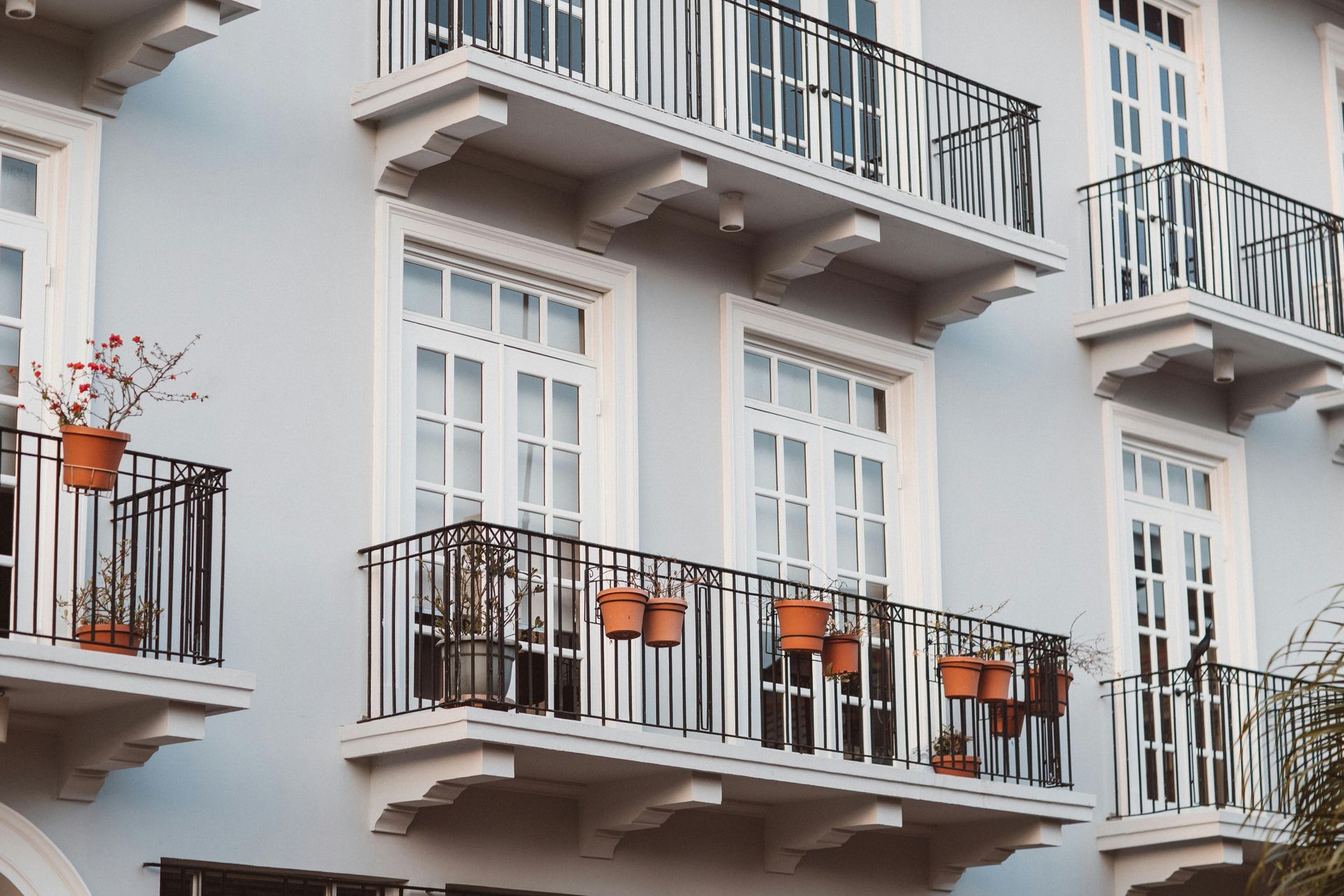 White balconies with black railings and orange chairs on a pale building facade