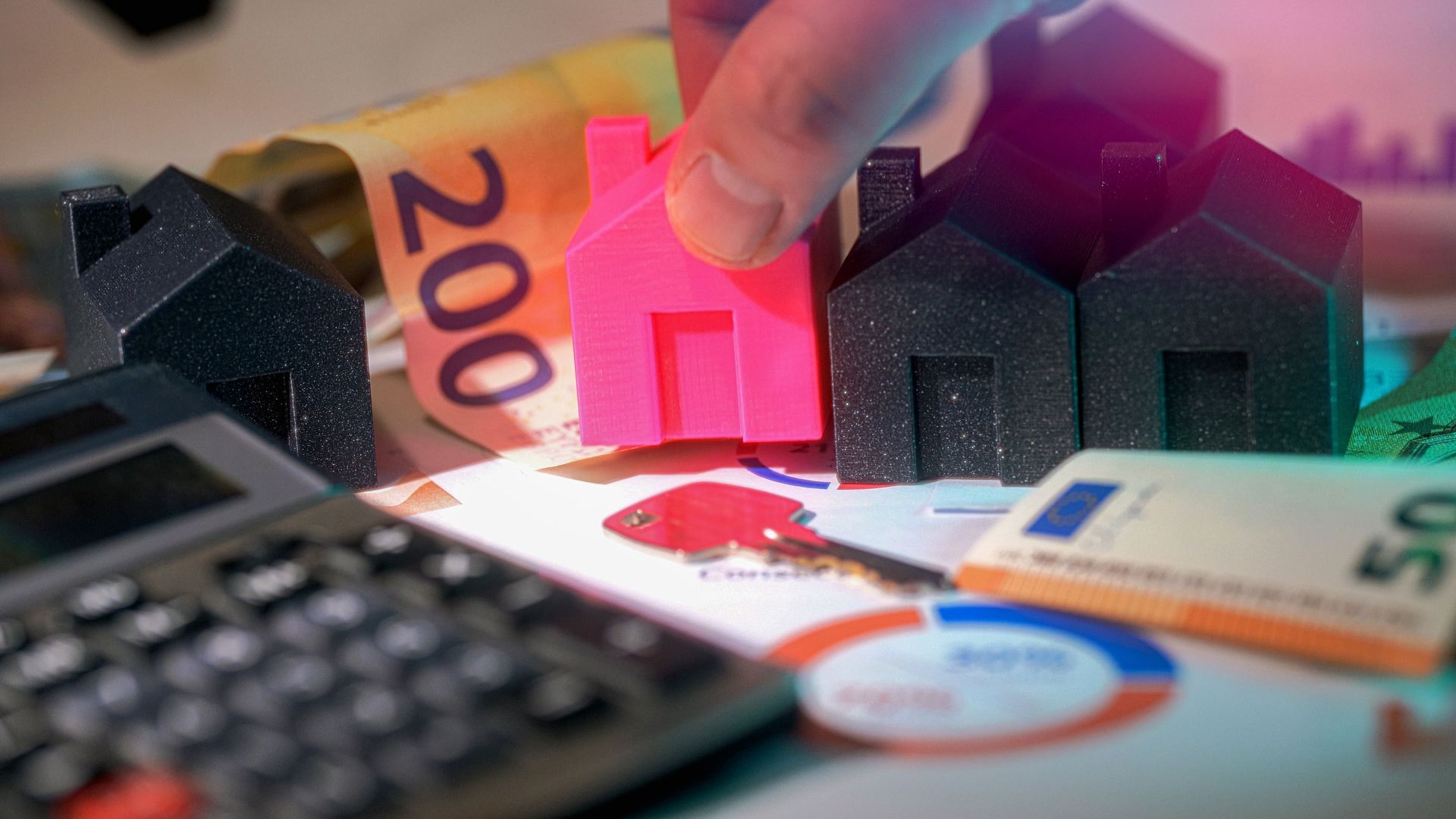 Hand placing a pink house model among black houses on euro banknotes, symbolizing property investment.