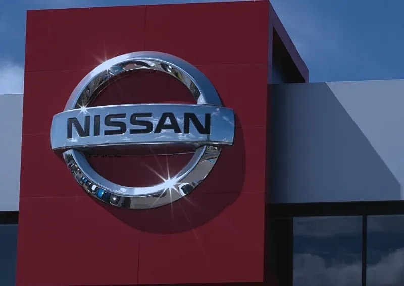 Nissan dealership sign on a red building facade against a blue sky
