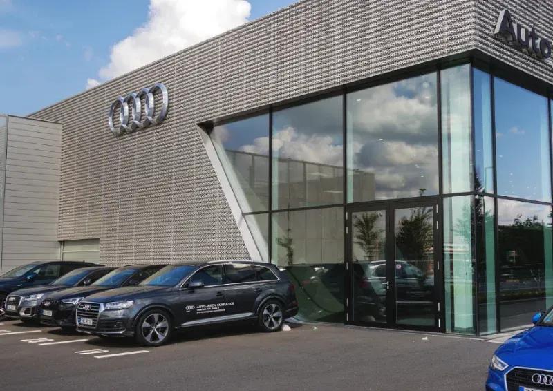 Audi dealership exterior with parked cars and large glass showroom windows