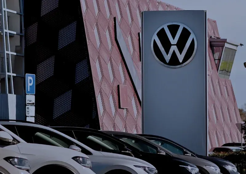 Volkswagen dealership sign above parked cars beside a modern building