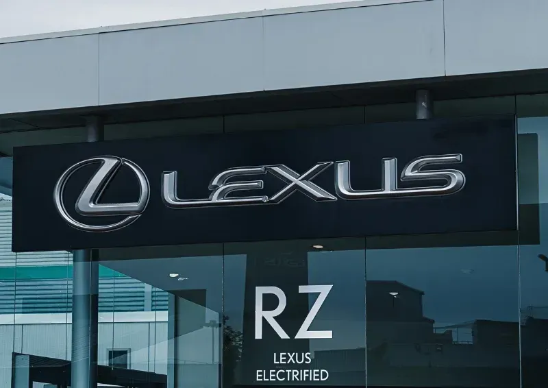 Lexus dealership sign with RZ and Lexus Electrified branding on a glass storefront