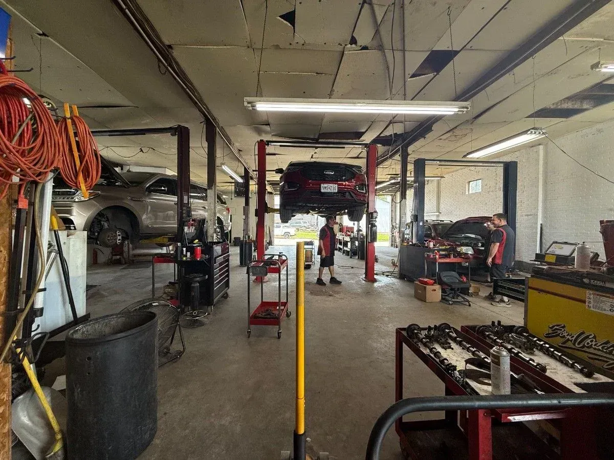 Auto repair shop interior in Cape Girardeau, MO with cars on lifts, tools, and hoses hanging from the ceiling