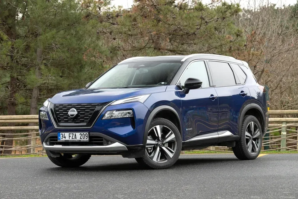 Blue SUV parked on a road with trees in the background