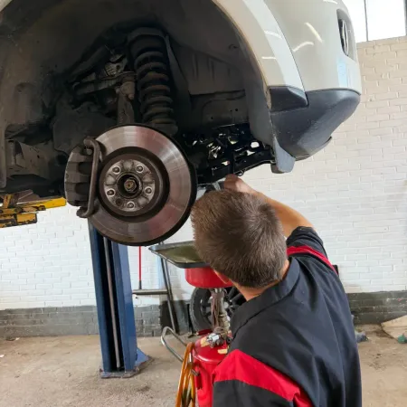 Mechanic inspecting a car’s front brake and suspension on a lift in a garage in Cape Girardeau, MO