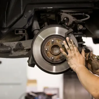 Mechanic’s hand inspecting a car’s brake rotor and caliper during repair in Cape Girardeau, MO