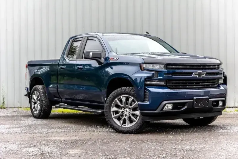 Blue Chevrolet pickup truck parked in front of a white corrugated wall