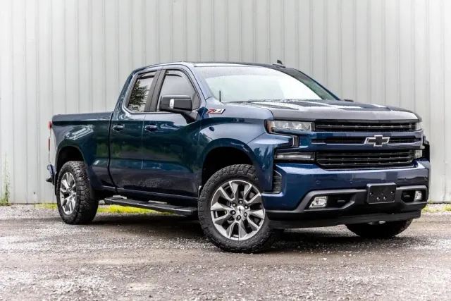 Dark blue Chevrolet pickup truck parked beside a white corrugated wall.