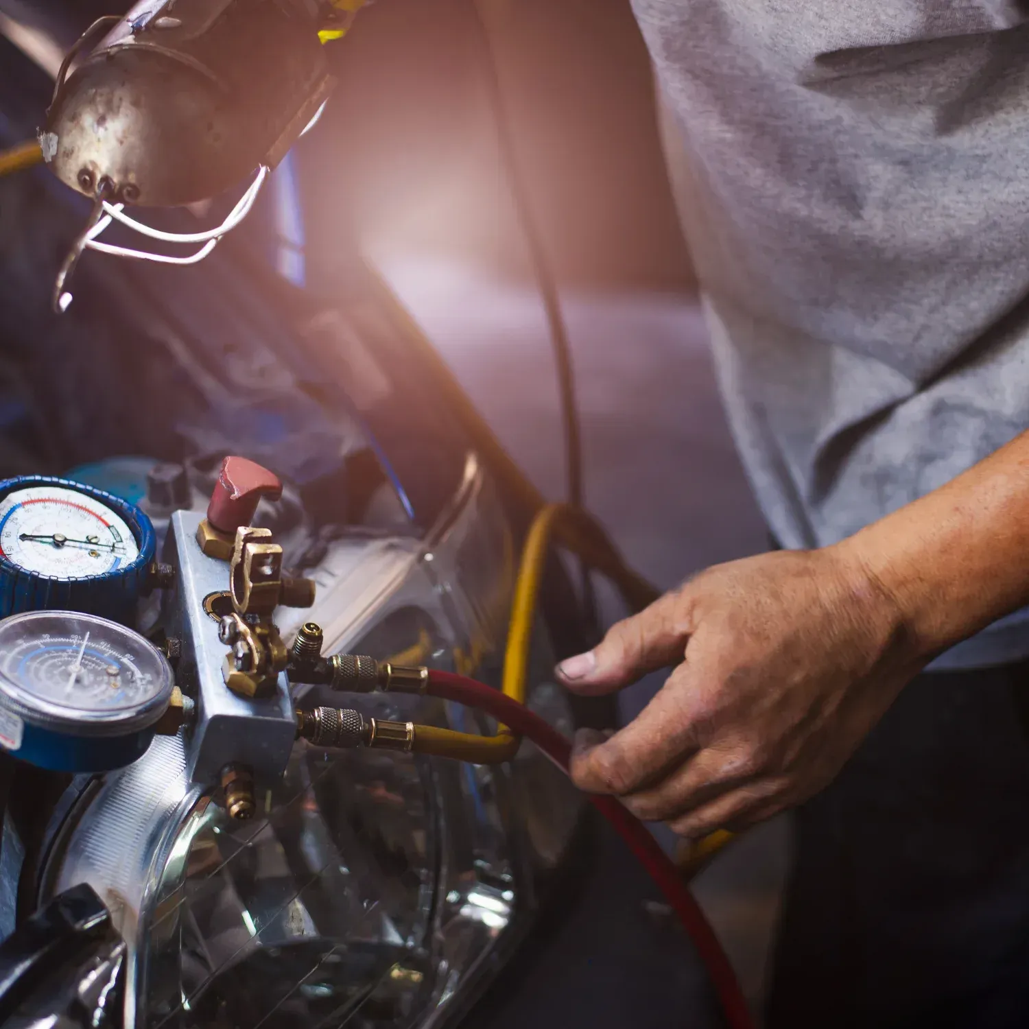 Technician in Cape Girardeau, MO connecting hoses to an air conditioning compressor with pressure gauges attached