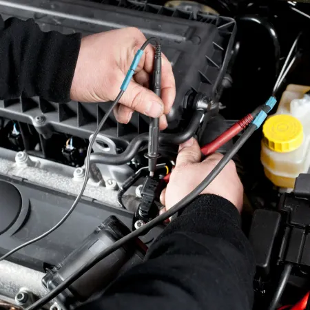 Hands using a test probe on a car engine bay near the battery and fluid reservoir in Cape Girardeau, MO