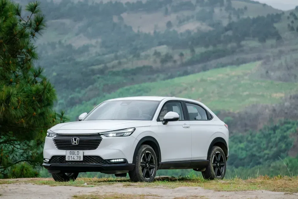 White SUV parked on grass with misty green hills in the background