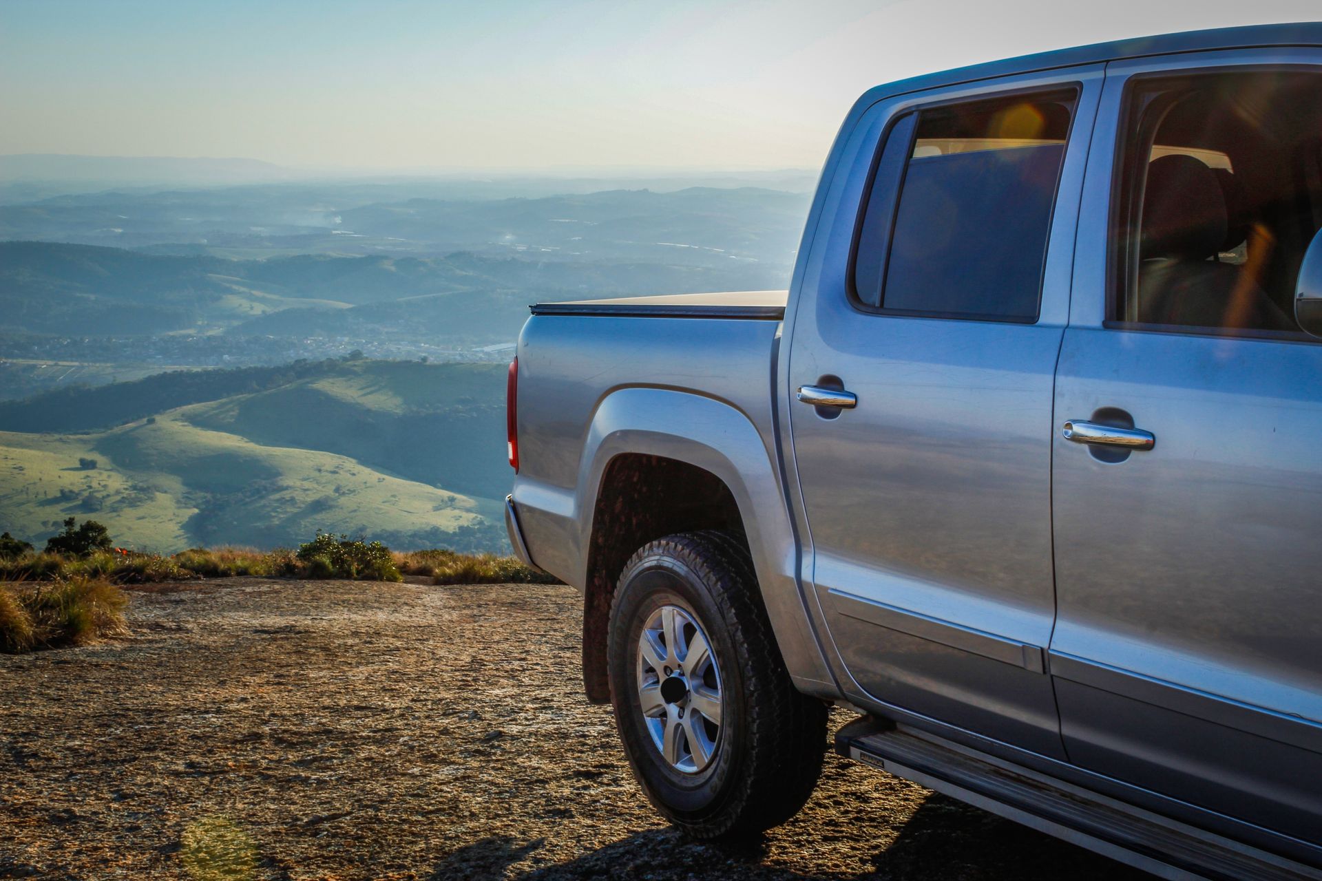 Silver pickup truck parked on a mountain overlook with a scenic valley in the background