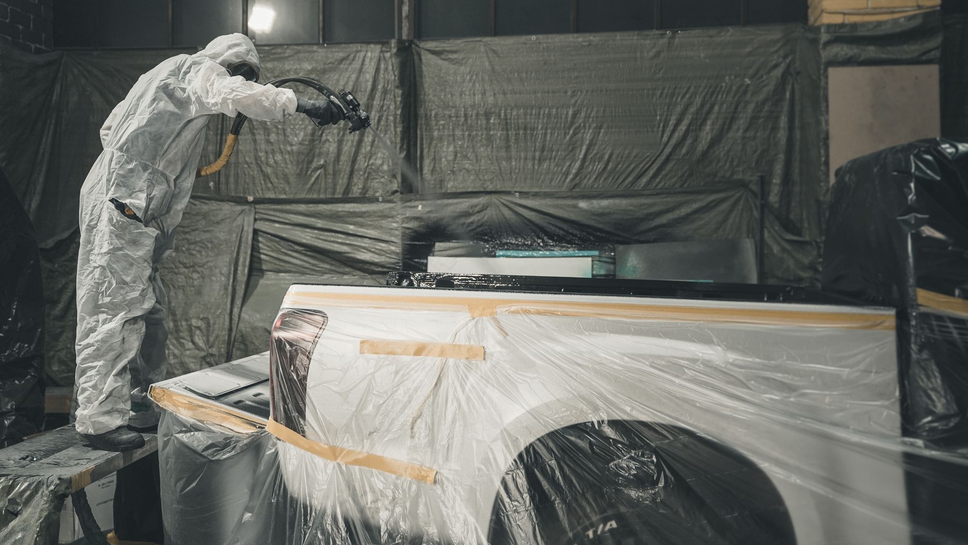 Technician applying Rhino Linings spray-on coating to a Chevy Silverado bed, Baton Rouge shop