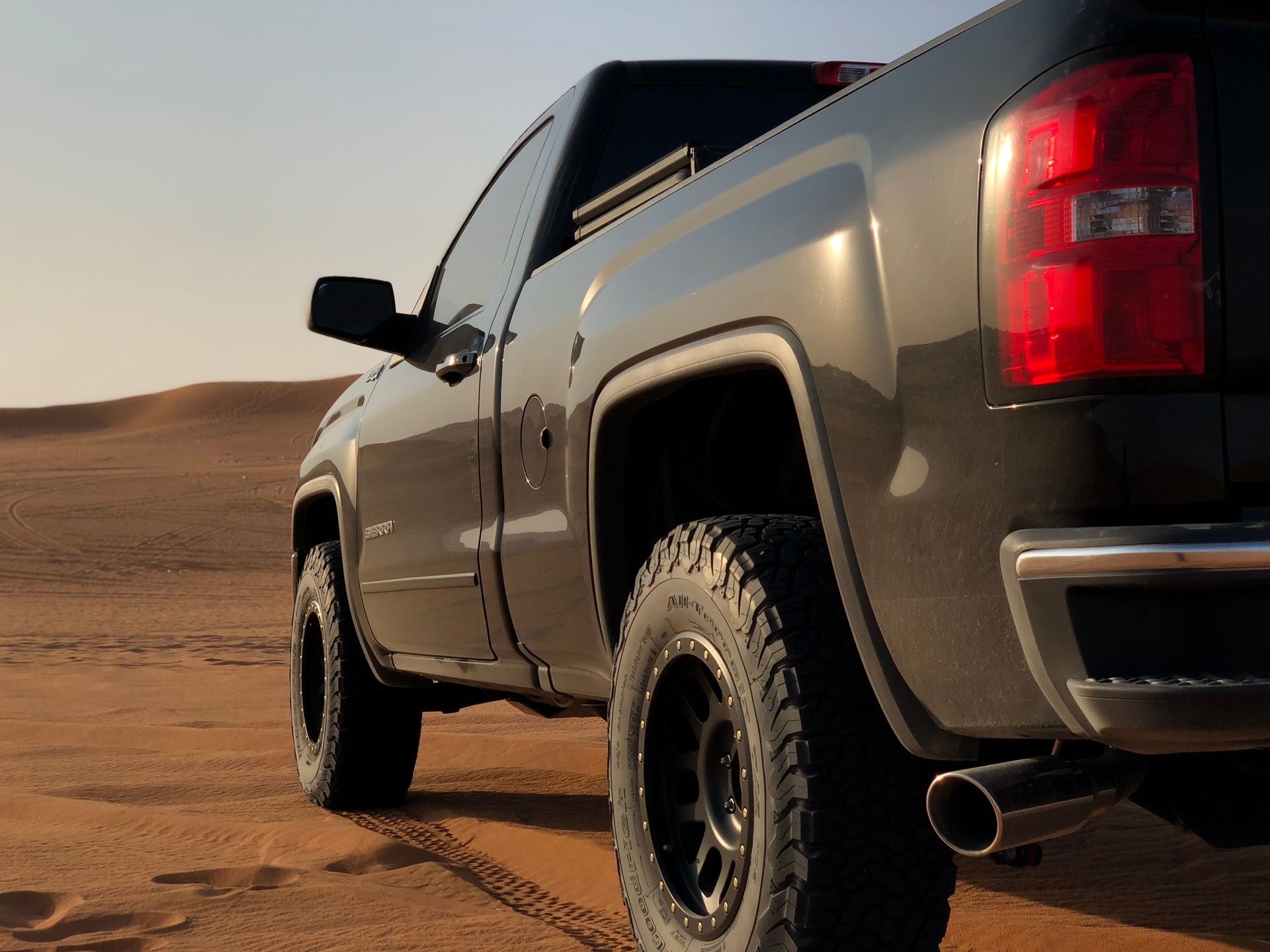 Gray pickup truck driving on desert sand dunes