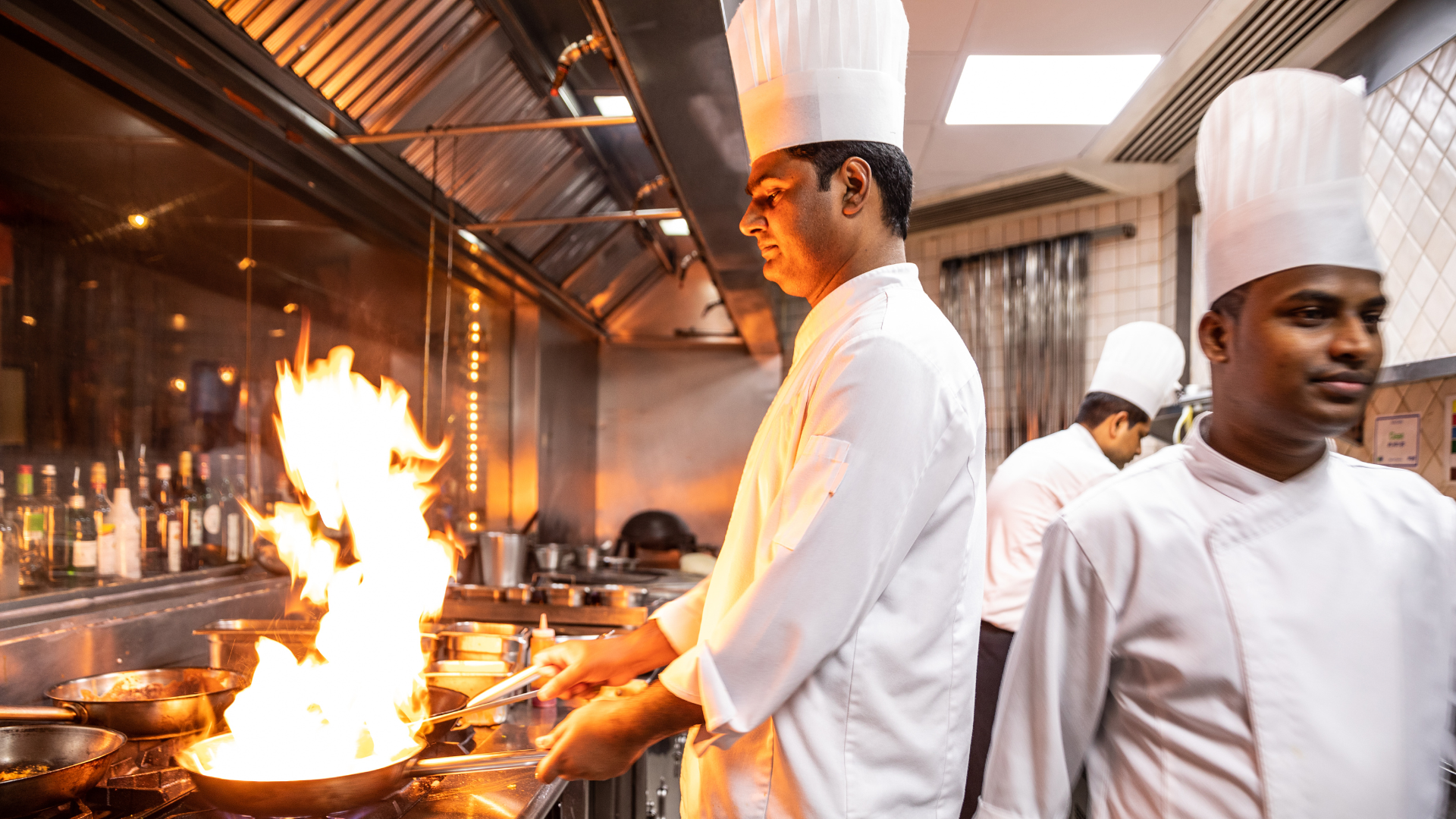 A group of chefs are cooking food in a kitchen.