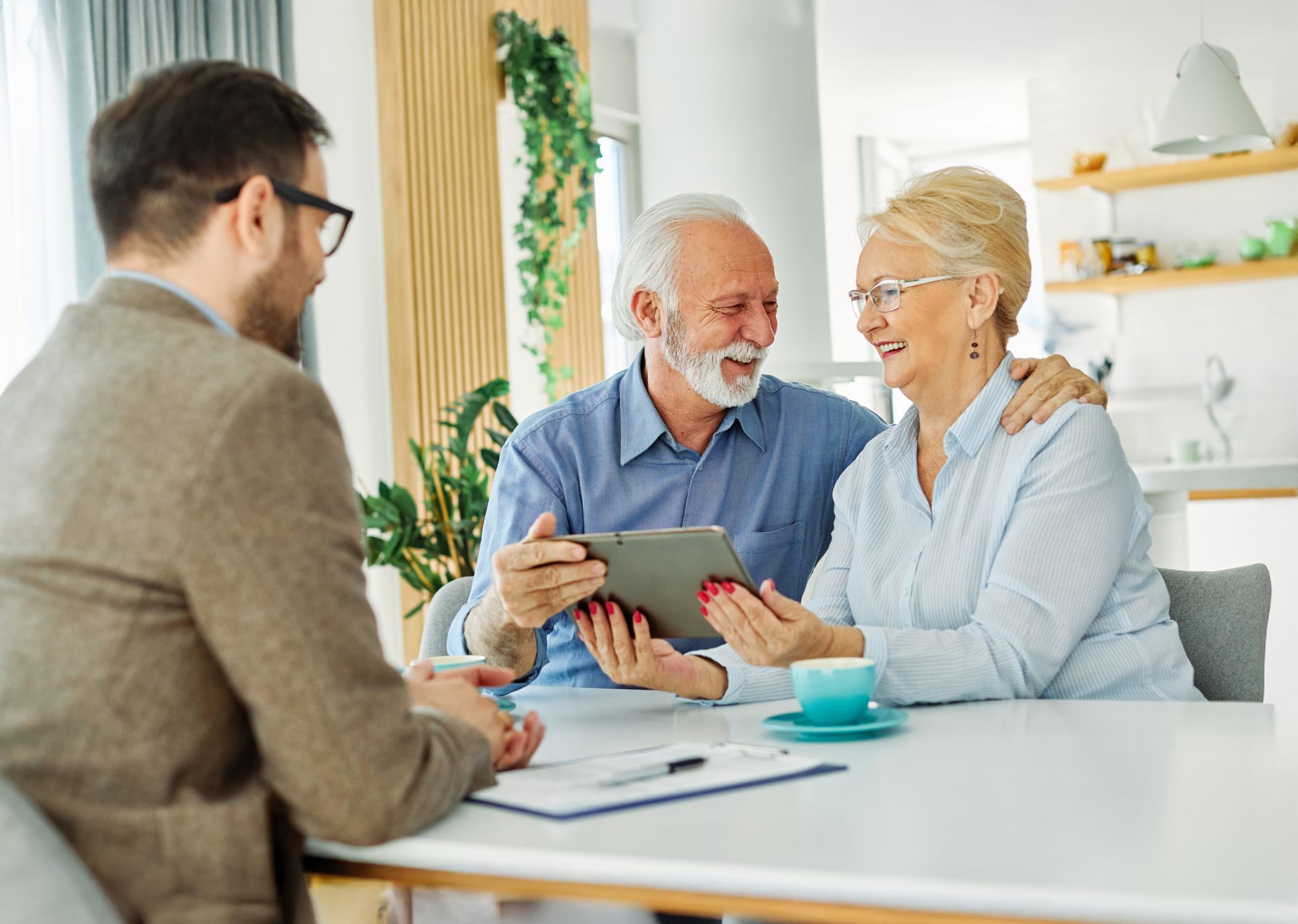 Three people discussing a tablet at a bright table in a modern office