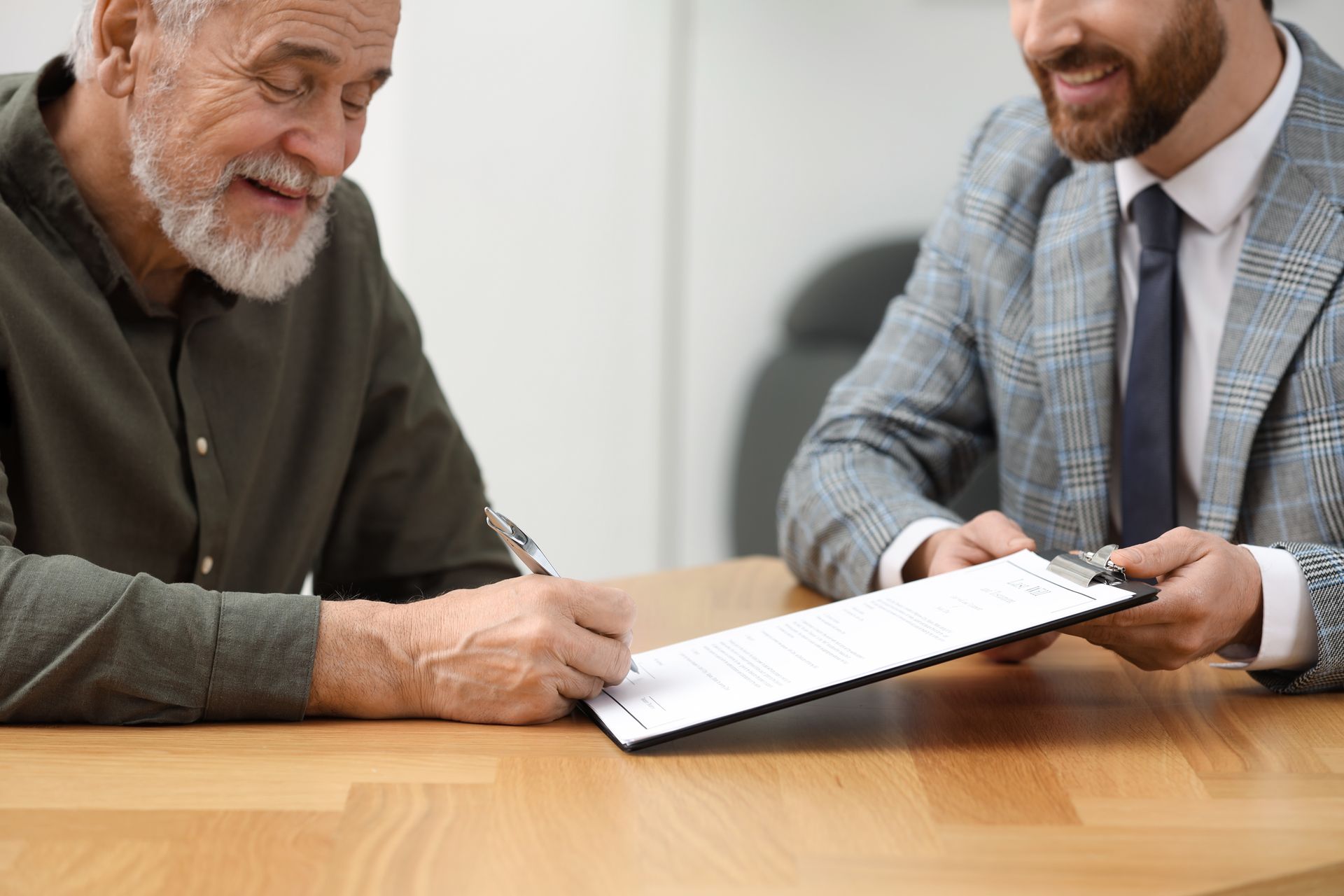 Two people reviewing documents at a wooden table in an office setting
