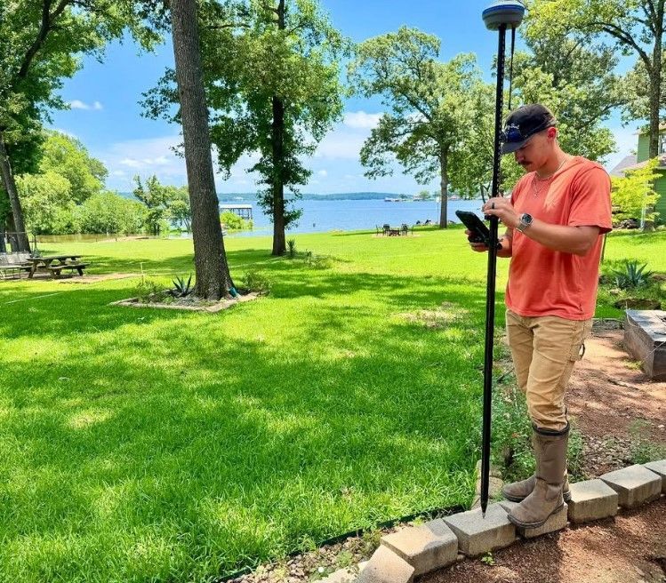 A man is standing in a park looking at a tablet.