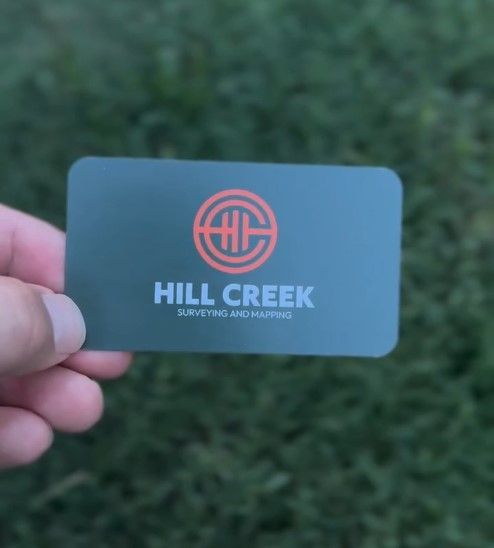 A person is holding a business card that says hill creek 