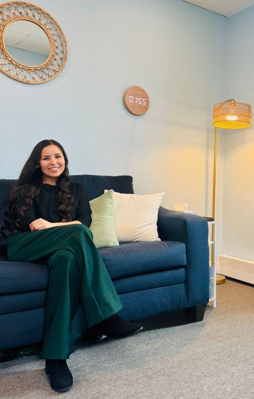 Woman sitting on a blue couch in a light blue living room with decorative wall art and a floor lamp