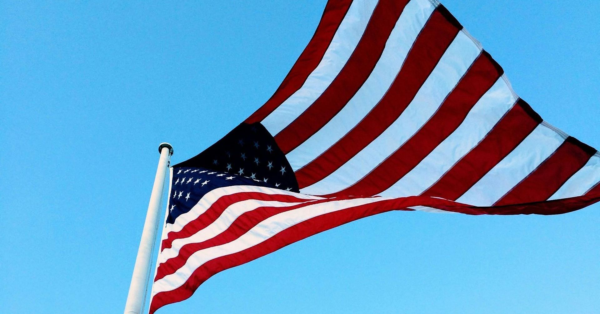 American flag waving against a clear blue sky.