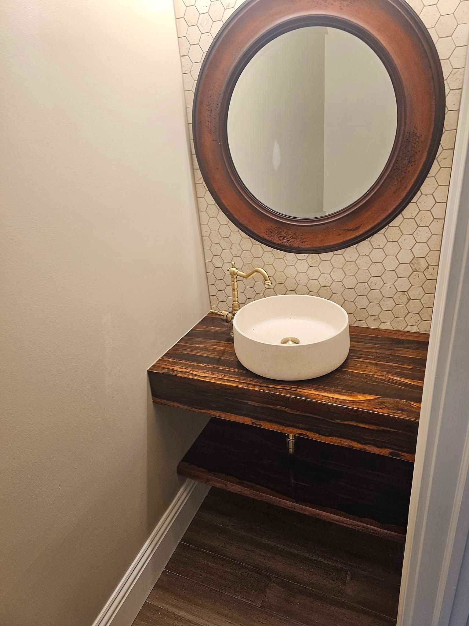 Small rustic bathroom vanity with round mirror, white vessel sink, and dark wood countertop.