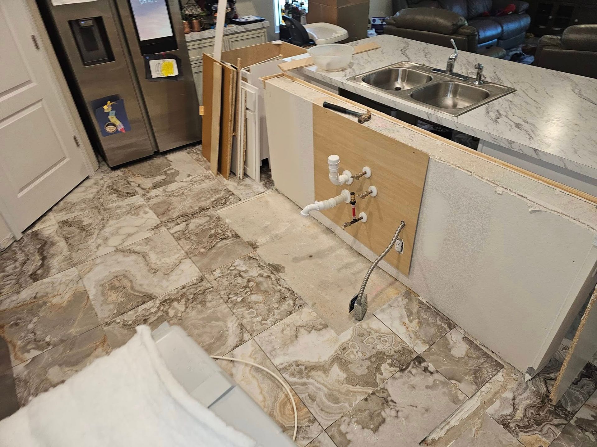 Kitchen under renovation with exposed floor, white cabinets, and sink area near a doorway.