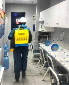 Un trabajador con una mochila pulverizadora amarilla camina por una zona de cocina de laboratorio