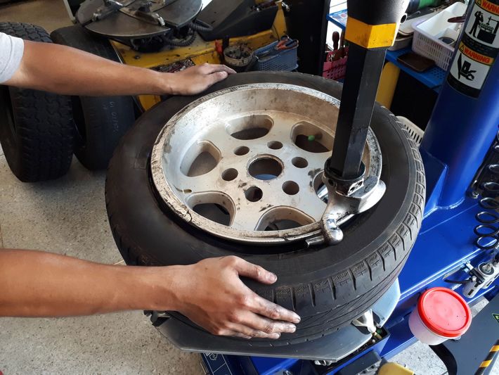 Mani che rimuovono uno pneumatico da un cerchione con una macchina smontagomme in un'officina