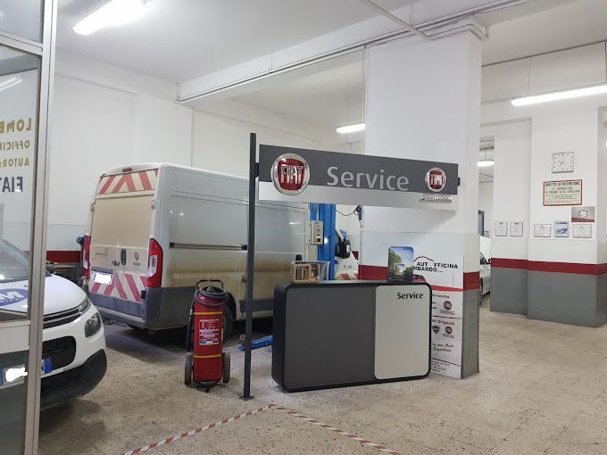 Banco di assistenza auto all'interno di un'officina, con furgone, auto e attrezzatura rossa da stazione di servizio.