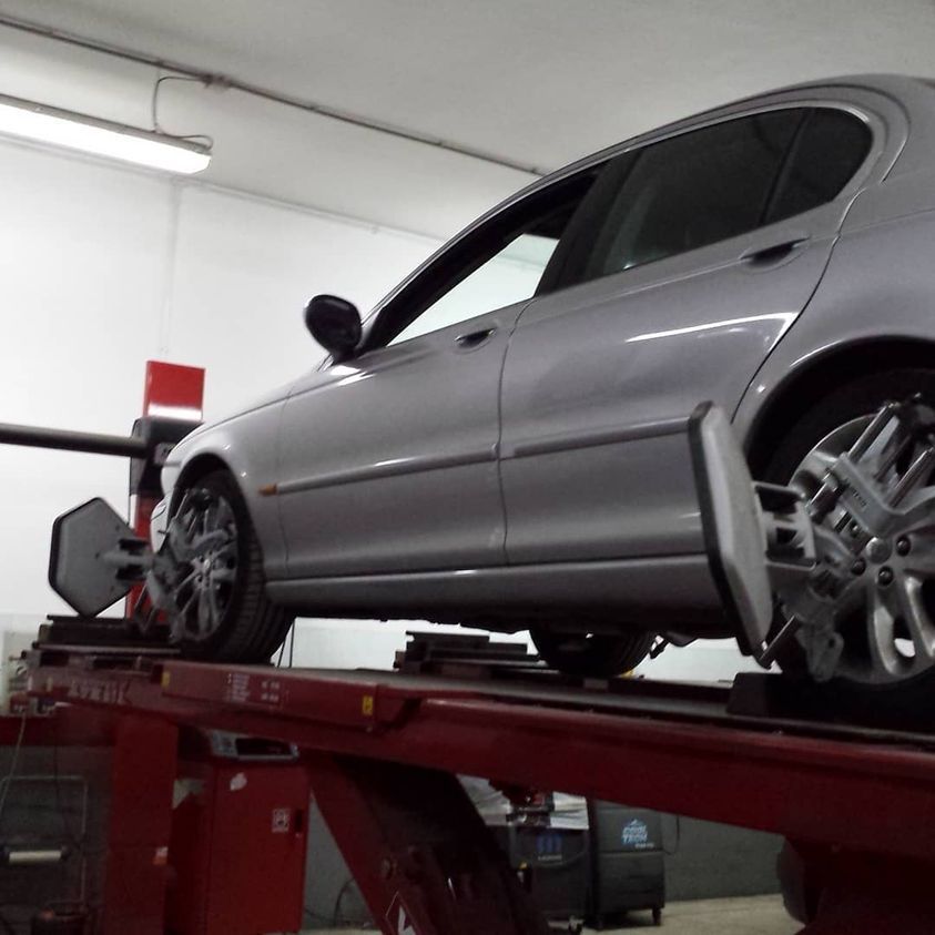 Auto grigia su un sollevatore idraulico rosso in un'officina meccanica.