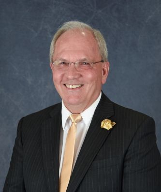 A man in a suit and tie is smiling for the camera