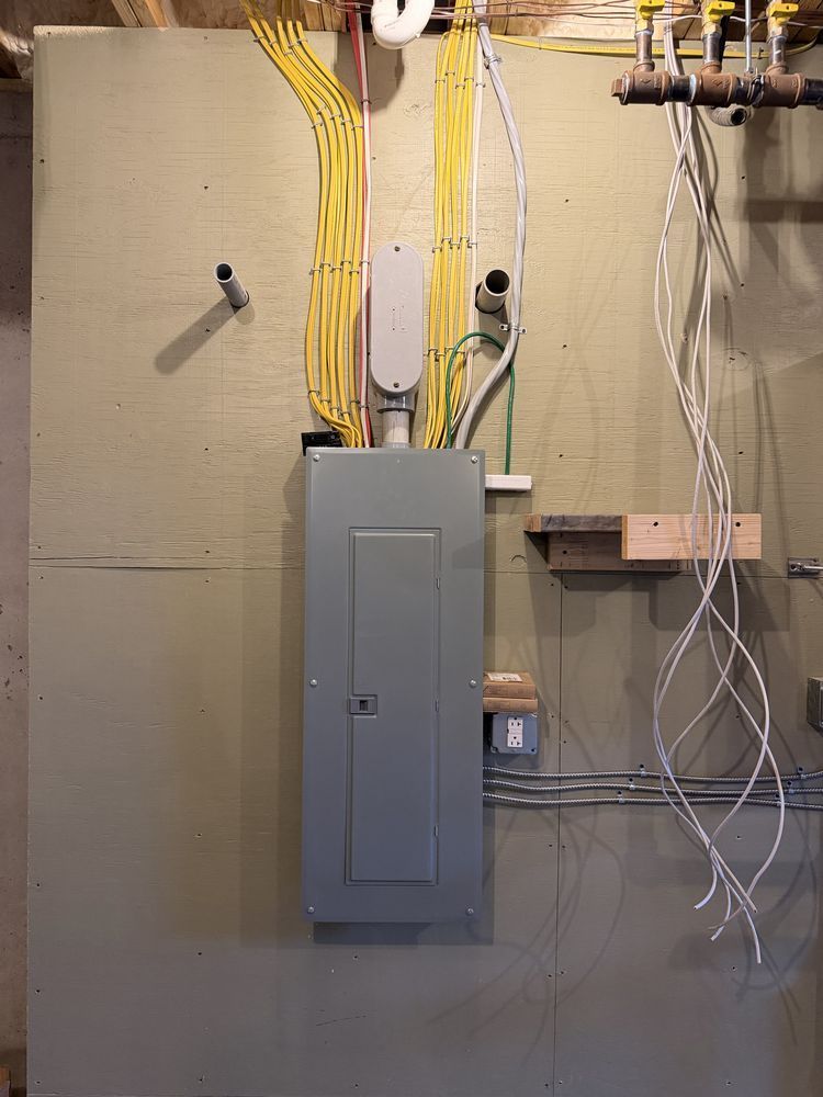Basement electrical panel with yellow and white wiring on a concrete wall.