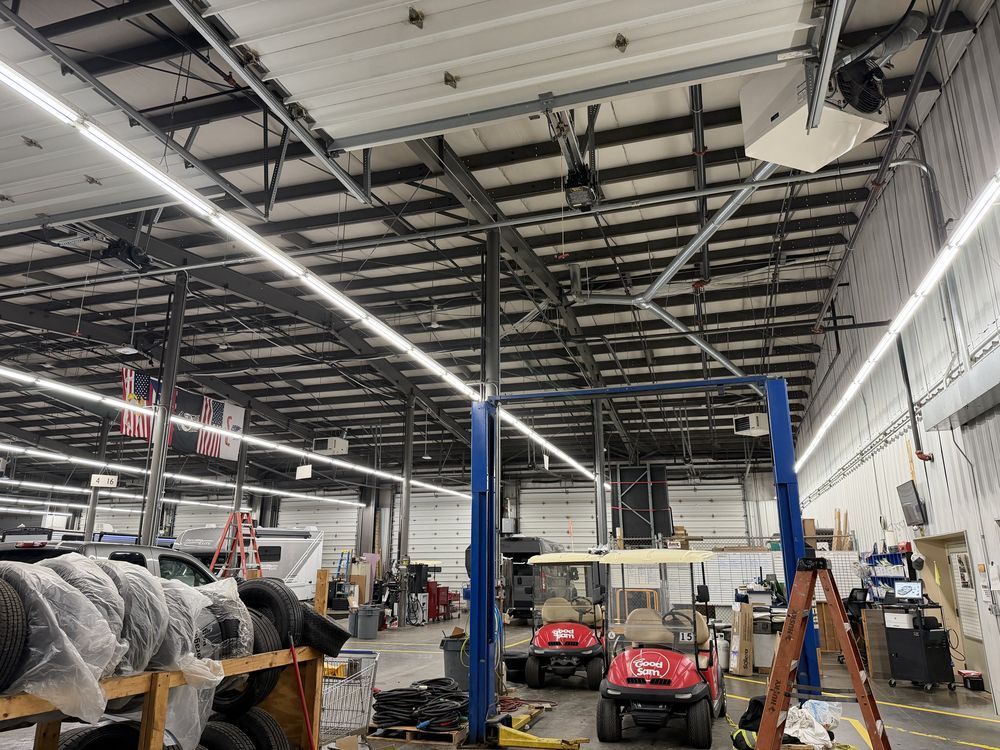 Auto repair shop with a lifted vehicle, red service cart, and high ceiling with exposed beams