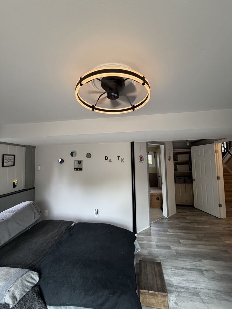 Bedroom with black bedspread, round ceiling light, gray walls, and open doors to a hallway.