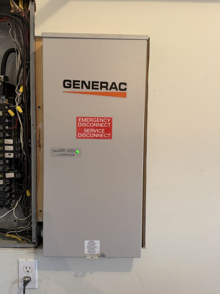 Gray Generac generator cabinet mounted on a wall beside electrical panels with a red warning label
