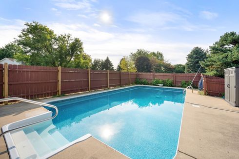 Inground swimming pool with concrete deck and safety fence surrounding the pool area. Inground swimming pool with concrete deck and safety fence surrounding the pool area.