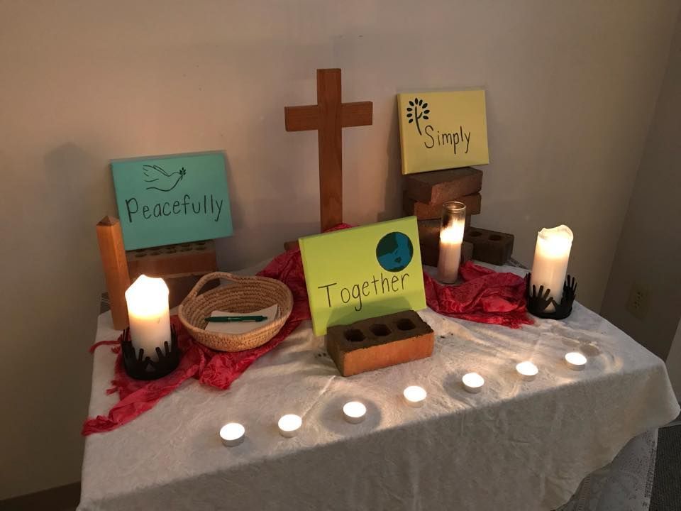 A table with a cross , candles , signs and a basket on it.
