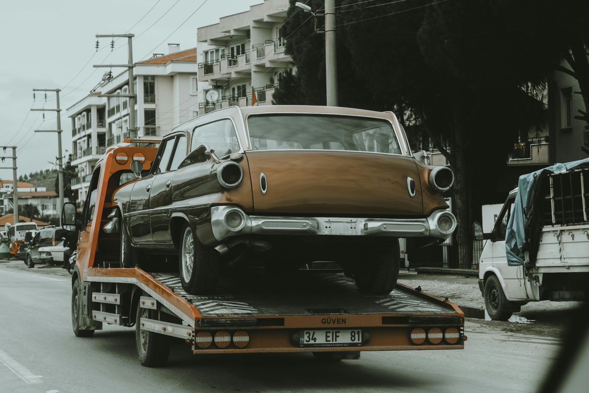 An old car is being towed by a tow truck.
