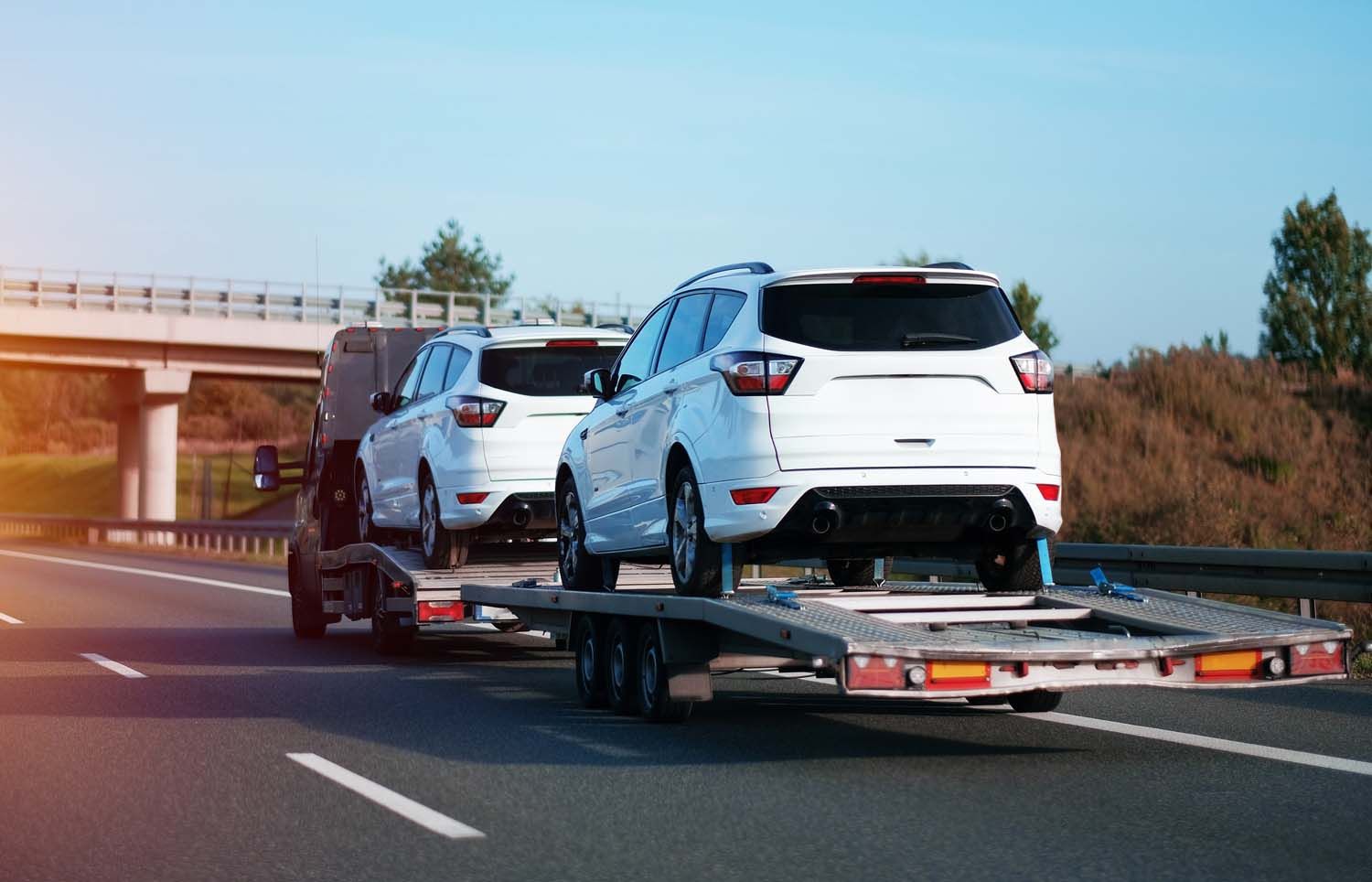A tow truck is towing a row of cars on a highway.