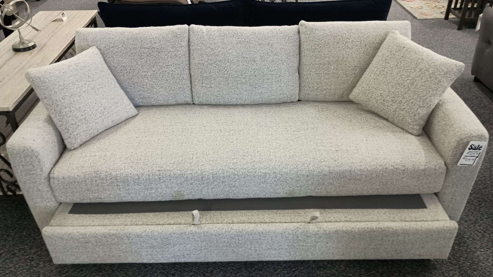 Beige sofa with pull-out bed, two matching pillows, and textured upholstery.