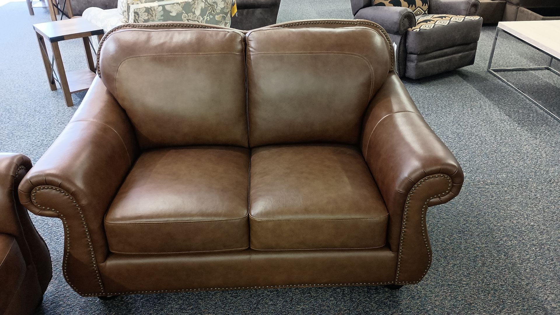 A brown leather couch with studs on the arm rests