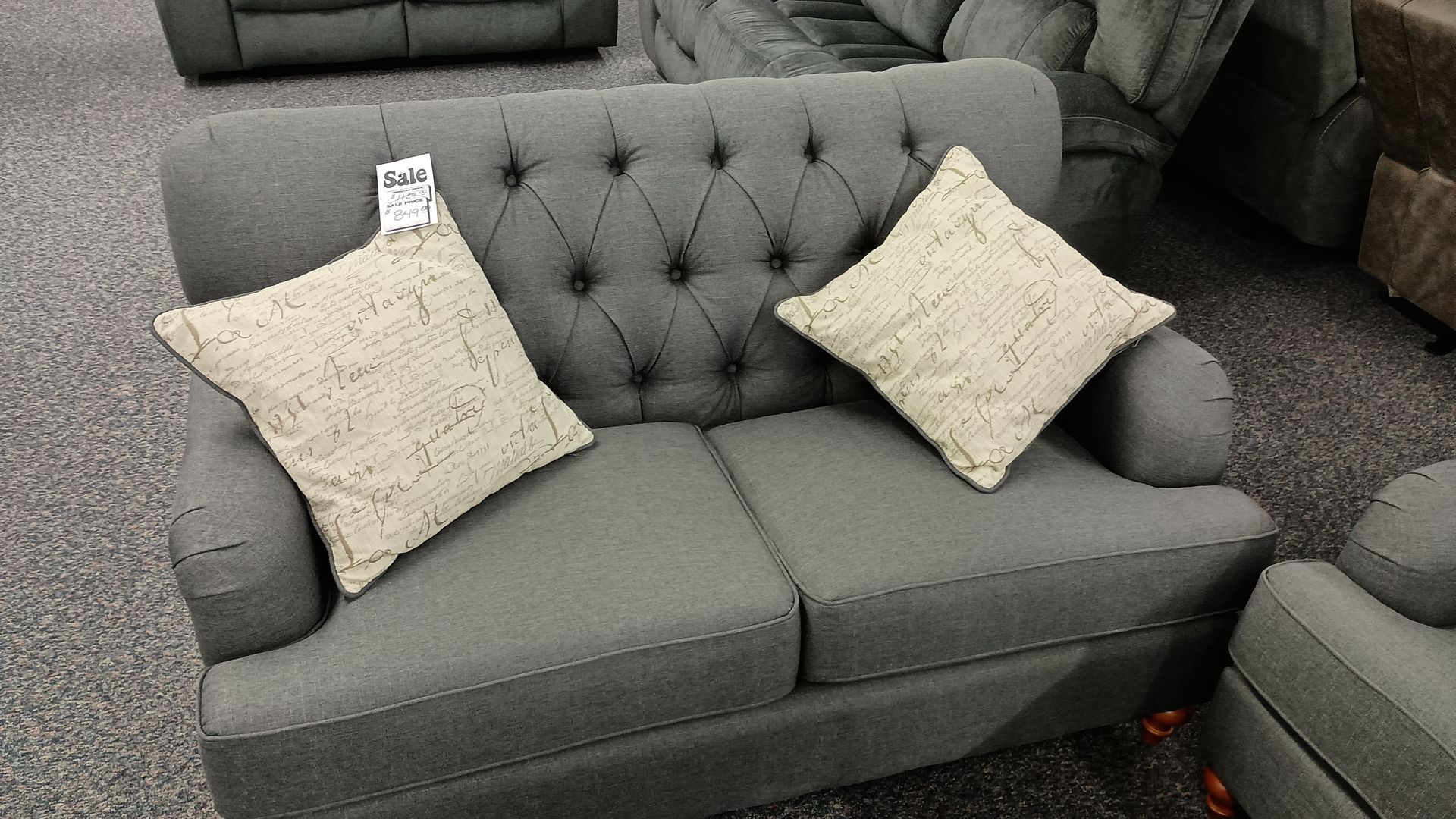 A grey tufted couch with two pillows on it