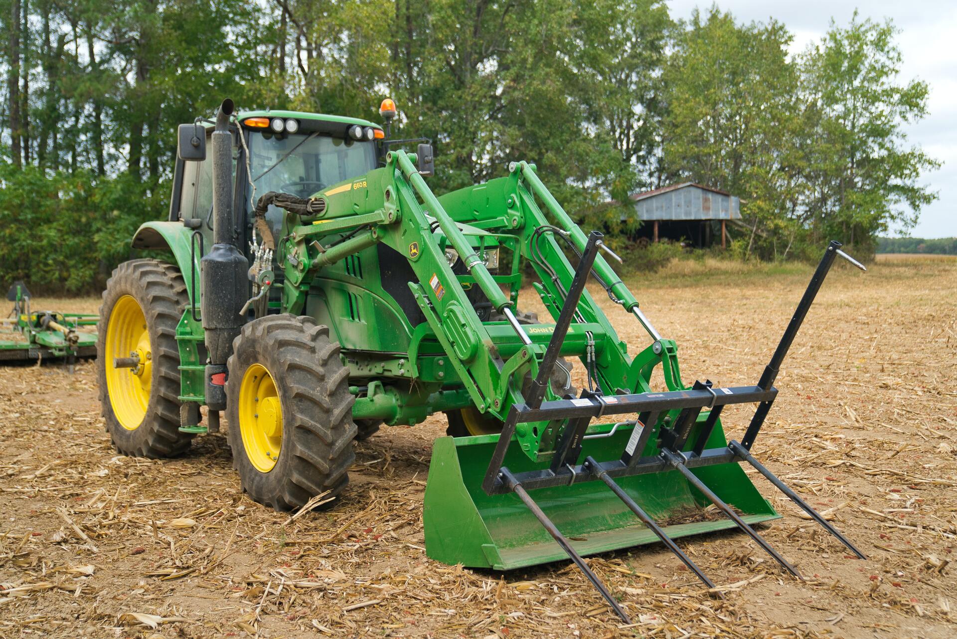 A green digger on a mulched ground in front of trees.