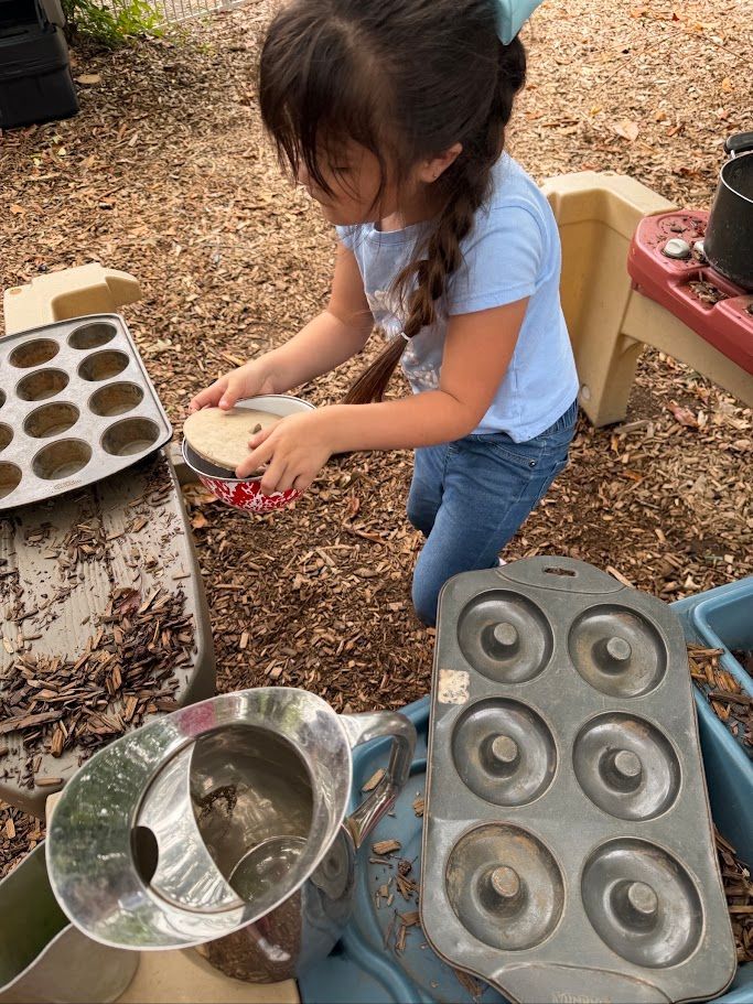 Child outdoors pouring seeds into muffin tins for a garden project