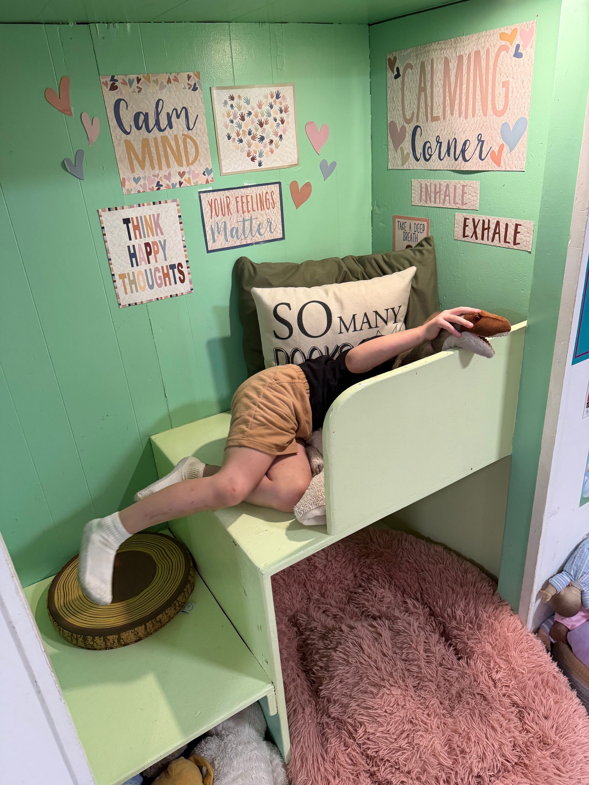 Person lounging on a cat shelf in a mint-green room with wall art and a pink carpeted ramp
