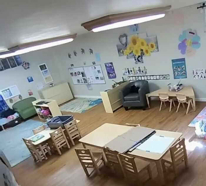 Bright preschool classroom with tables, chairs, shelves, rugs, and colorful wall decorations